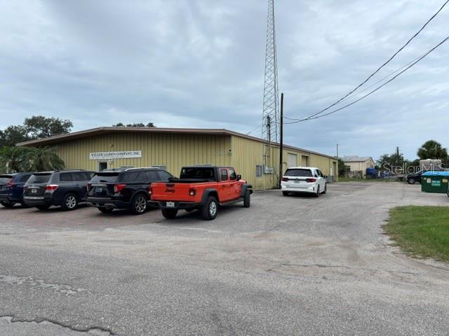 An exterior view of a commercial building with a tall radio tower and parked vehicles — 5654 SARAH AVENUE, SARASOTA, FL