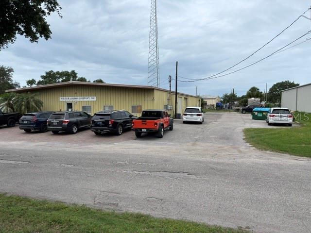 A single-story commercial building with a parking lot containing several vehicles and a radio tower — 5654 SARAH AVENUE, SARASOTA, FL