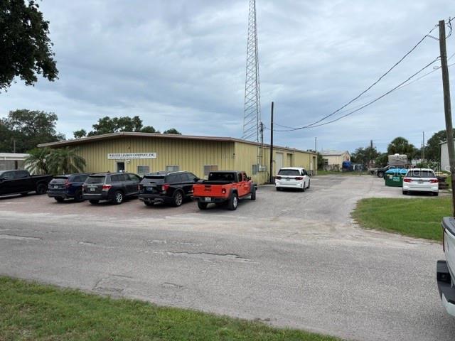 A commercial building with a metal exterior and a tall radio tower stands outdoors — 5654 SARAH AVENUE, SARASOTA, FL