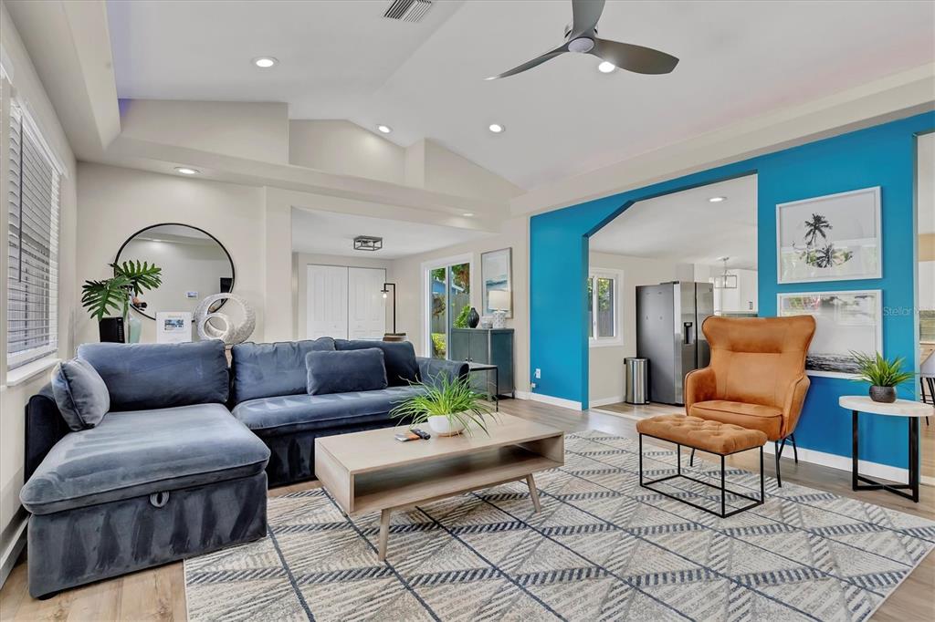 A living room features a blue sectional sofa, a tan armchair with ottoman, and blue walls — 4110 IOLA DRIVE, SARASOTA, FL