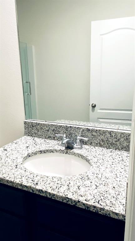 A bathroom vanity features a granite countertop, an oval sink, and a large wall mirror — 1128 FOX PATH, DAVENPORT, FL