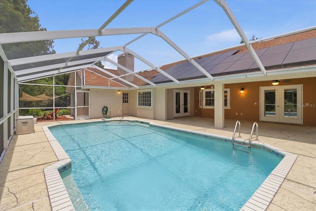 A screened-in swimming pool patio with a tan deck and solar panels on the roof — 45 HOLLYHOCK COURT, HOMOSASSA, FL