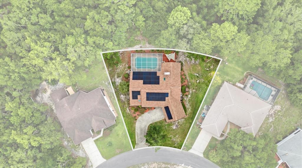 An aerial view shows a house with solar panels, a screened pool, and a driveway — 45 HOLLYHOCK COURT, HOMOSASSA, FL