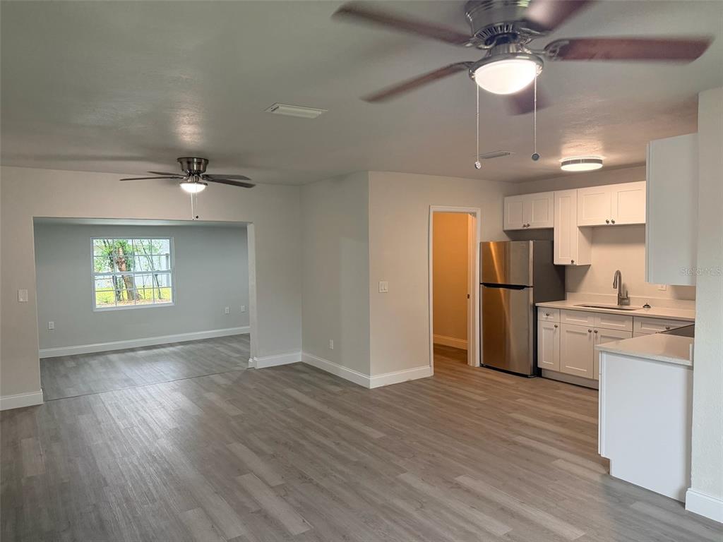A kitchen with white cabinets and stainless steel appliances opens into a living area — 1869 W FREEMAN PLACE, CITRUS SPRINGS, FL