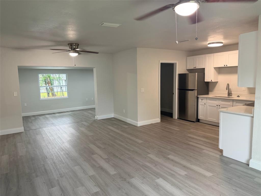An open-concept living area features light wood-look flooring, a kitchen with white cabinets, and stainless-steel appliances — 1869 W FREEMAN PLACE, CITRUS SPRINGS, FL