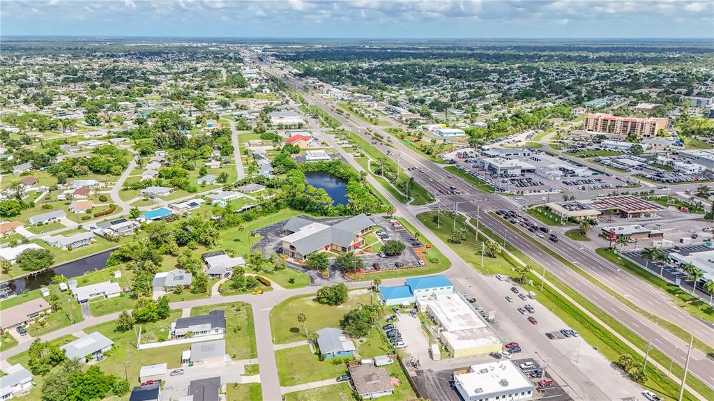 An aerial view shows a commercial building, surrounding residential properties, and a multi-lane highway — 3231 TAMIAMI TRAIL UNIT A-G, PORT CHARLOTTE, FL