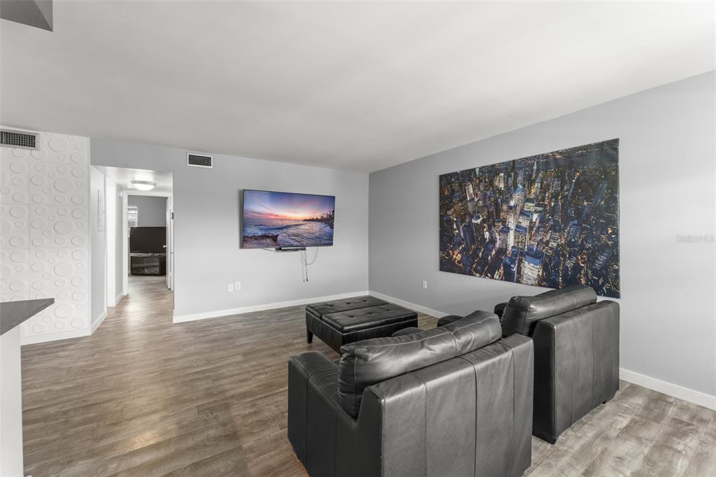 A living room features gray walls, wood-look flooring, a wall-mounted television, and black leather furniture — 2500 LEE ROAD UNIT 220, WINTER PARK, FL