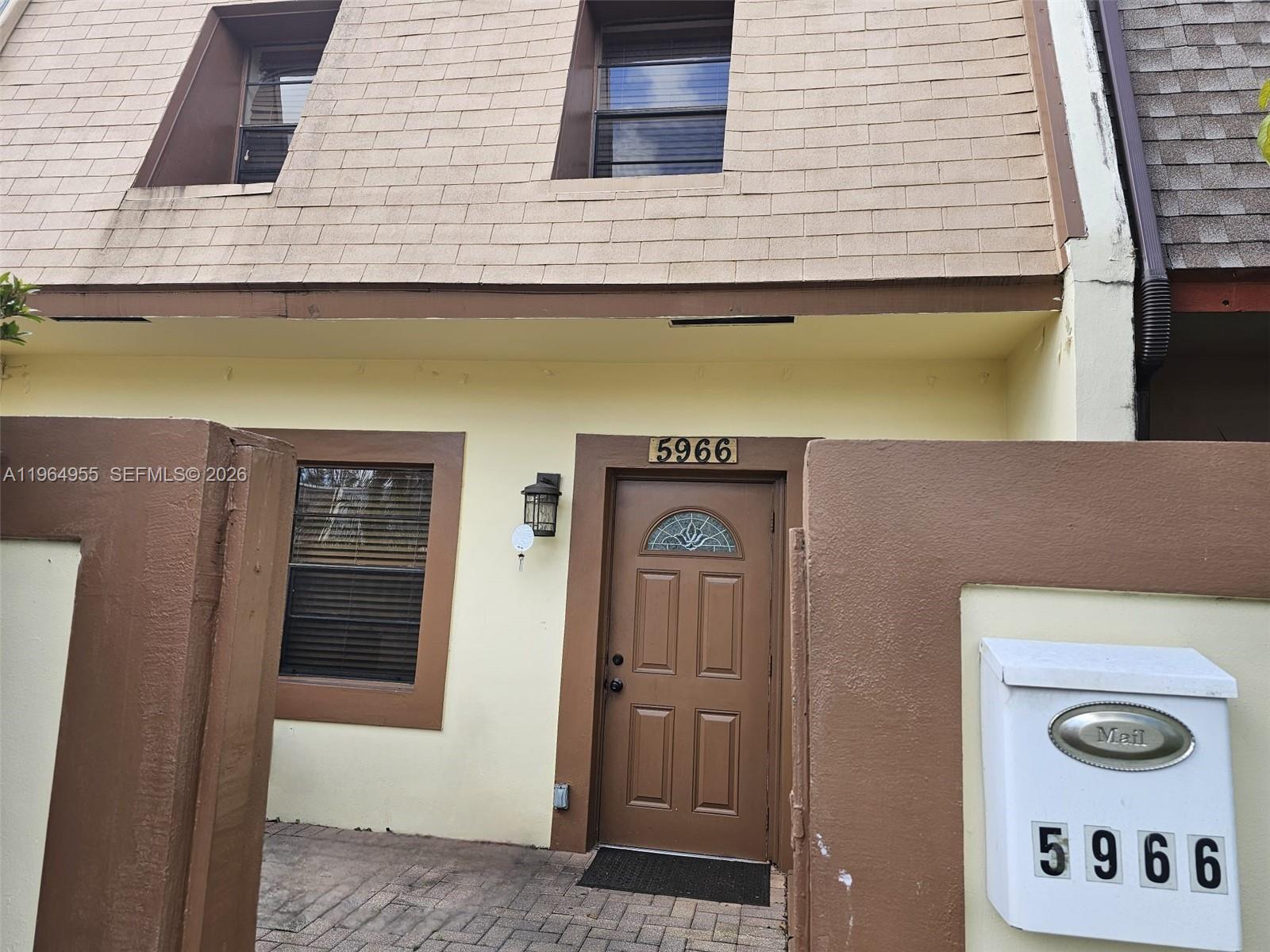 The exterior of a townhouse features a brown front door, a mailbox, and two windows — 5966 NW 24th Ct, Sunrise FL 33313, SUNRISE, FL