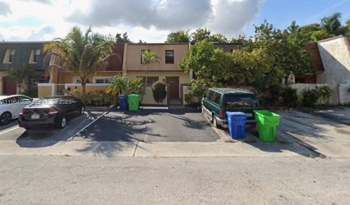 A two-story townhouse exterior with a paved parking area, two cars, and several trash bins — 5966 NW 24th Ct, Sunrise FL 33313, SUNRISE, FL