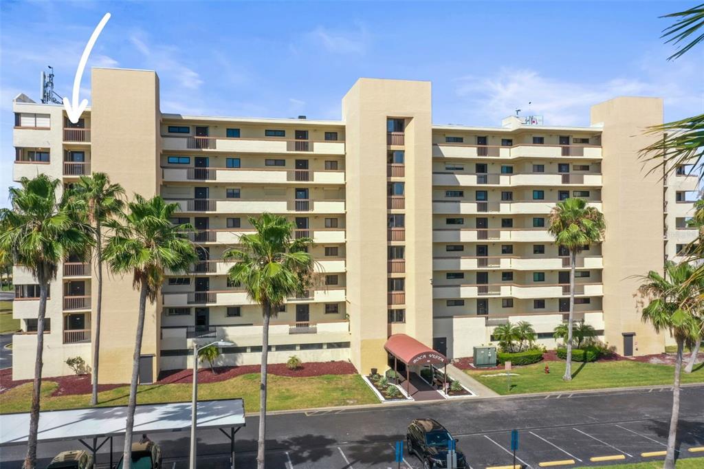 An exterior view of a multi-story apartment building with a white arrow pointing to a balcony — 401 150TH AVENUE UNIT 241, MADEIRA BEACH, FL