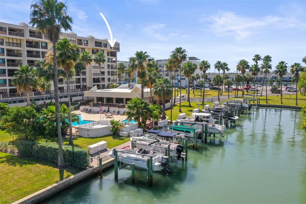 An exterior view of a multi-story waterfront condominium building with a boat dock and pool — 401 150TH AVENUE UNIT 241, MADEIRA BEACH, FL