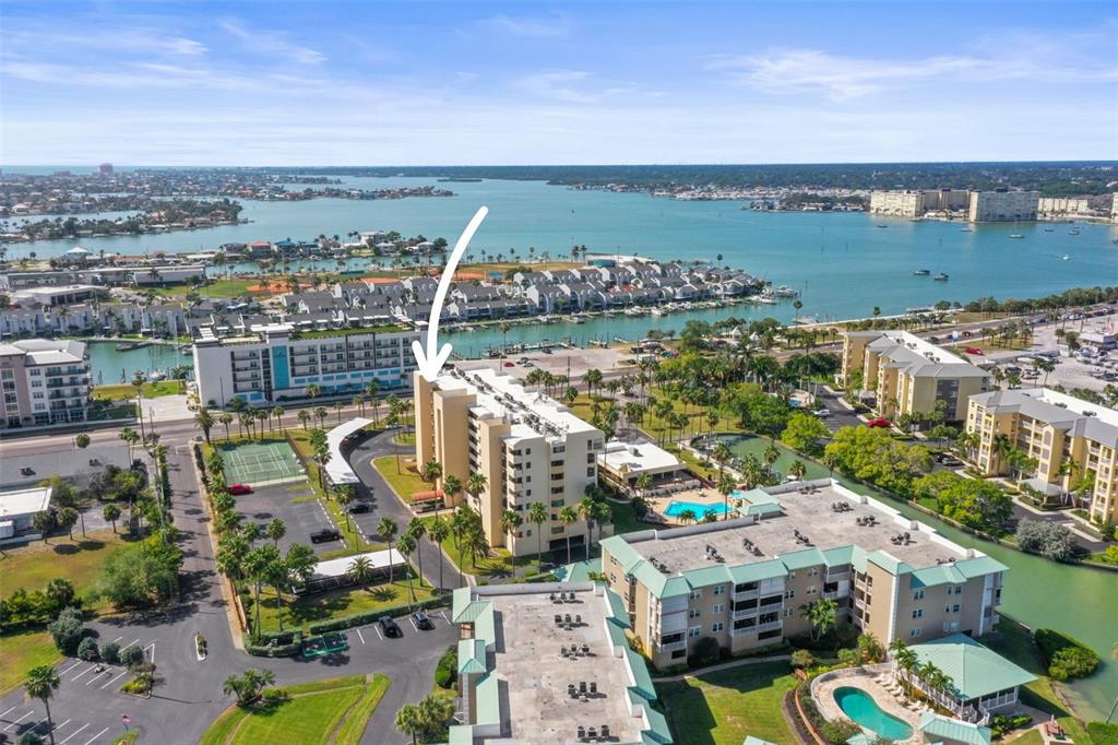 An aerial view of a multi-story apartment building near a bay with a tennis court — 401 150TH AVENUE UNIT 241, MADEIRA BEACH, FL