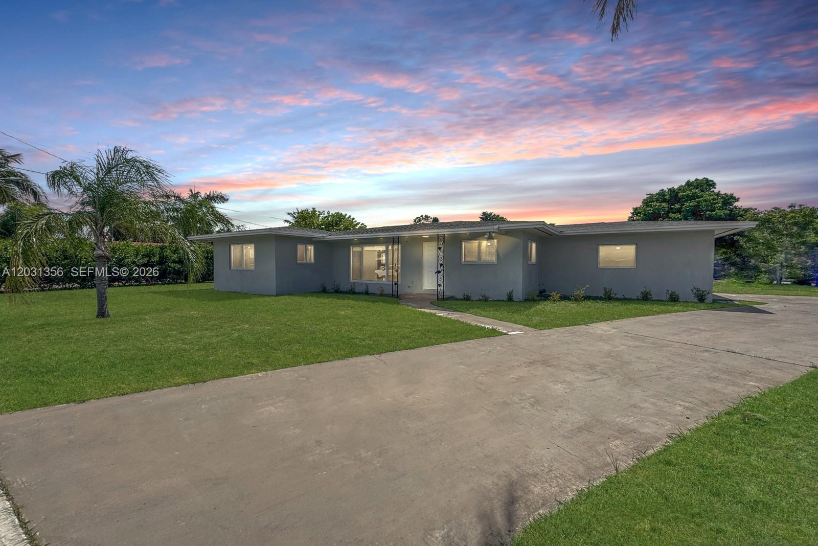 A single-story gray house with a concrete driveway and a palm tree at sunset — 231 NE 16th Ave, Pompano Beach FL 33060, POMPANO BEACH, FL