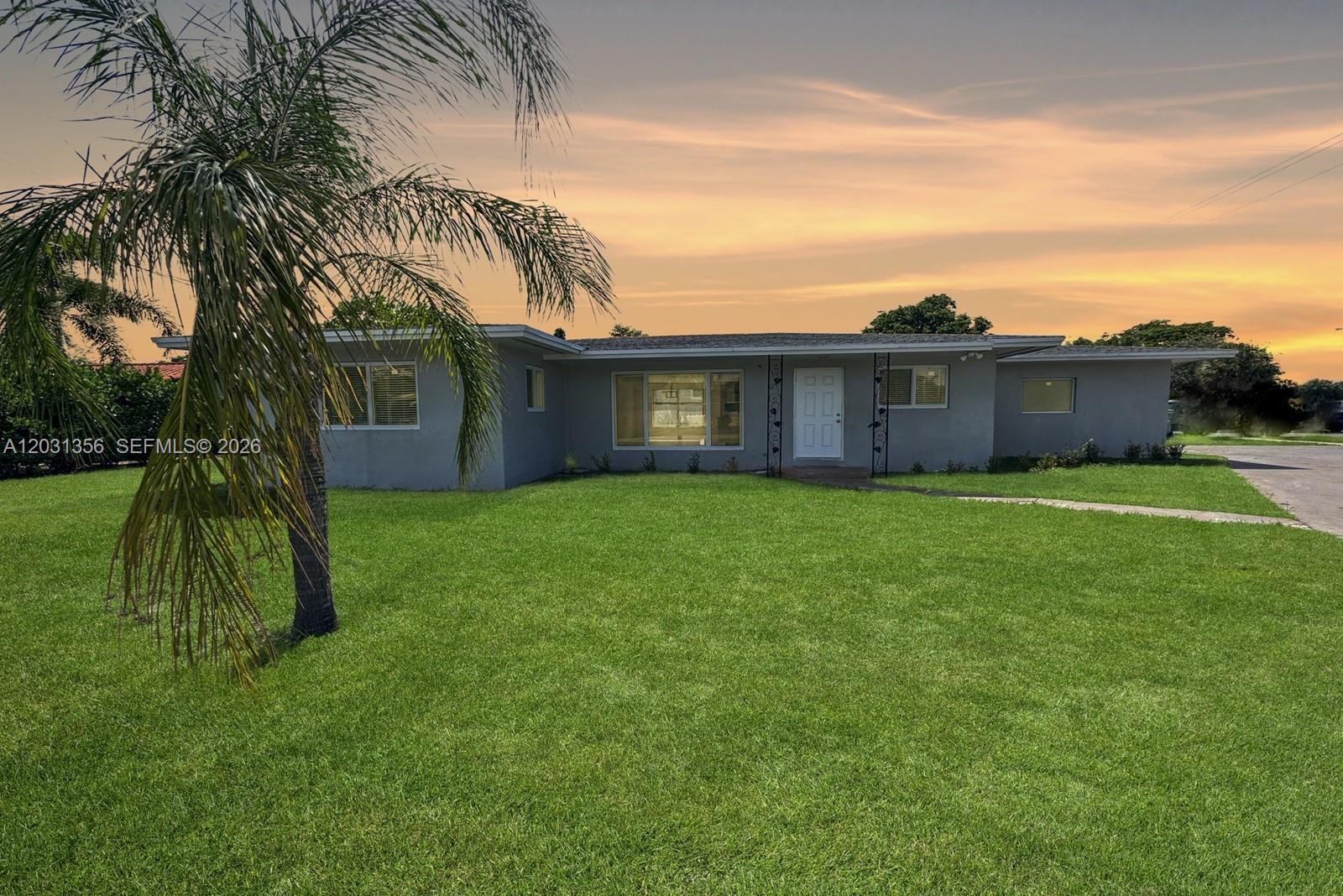 A single-story gray house with a front lawn and a palm tree at sunset — 231 NE 16th Ave, Pompano Beach FL 33060, POMPANO BEACH, FL