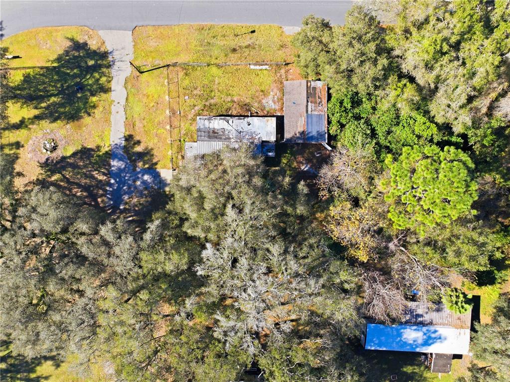 An aerial view shows a house with a metal roof surrounded by trees and grass — 4265 S ILLIANA TERRACE, INVERNESS, FL