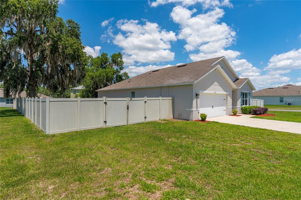 A beige single-story house with a white vinyl fence and a two-car garage — 10511 BURLWOOD DRIVE, LEESBURG, FL