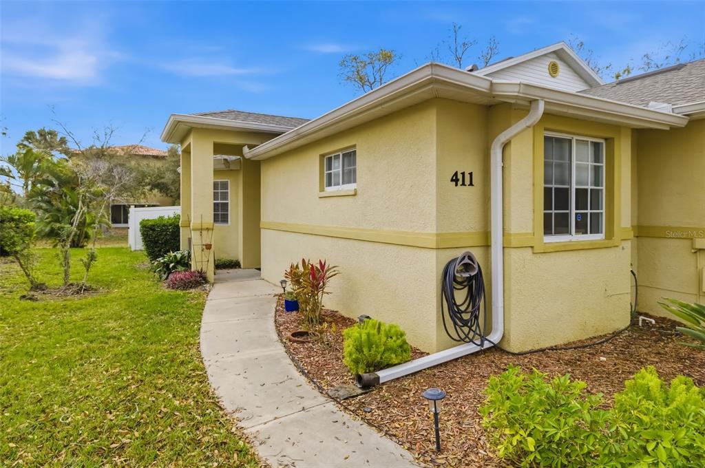 A yellow stucco house exterior features a concrete walkway leading to a recessed front entrance — 411 28TH STREET W, PALMETTO, FL