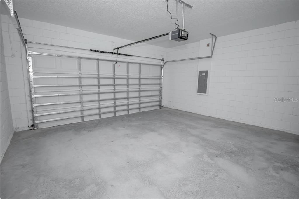 An empty garage with white concrete block walls, a metal door, and a concrete floor — 14587 SW 25TH TER, OCALA, FL 34473, OCALA, FL