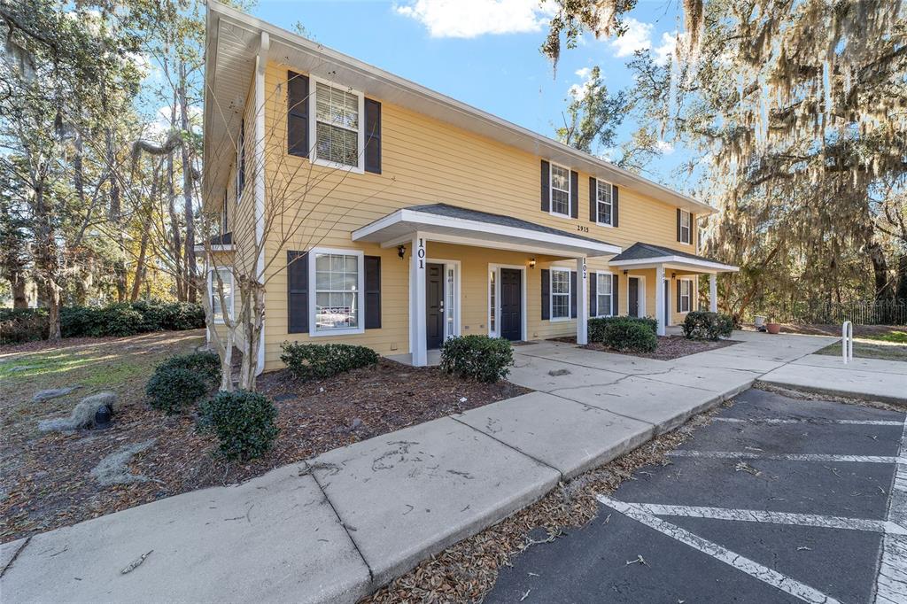 A two-story yellow building with multiple entrances and a concrete walkway in front — 2915 SW 35TH PLACE UNIT 102, GAINESVILLE, FL