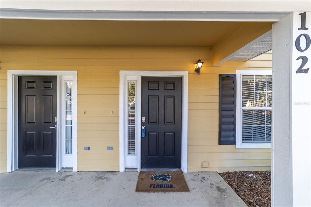 The exterior of a building shows two black front doors with a Florida Gators mat — 2915 SW 35TH PLACE UNIT 102, GAINESVILLE, FL