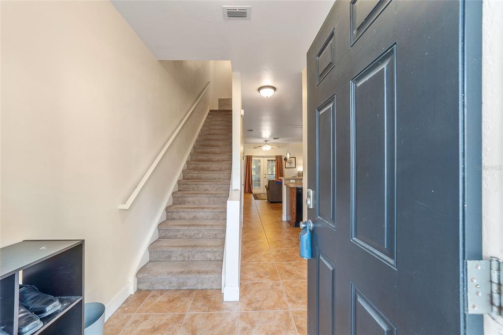 An entryway features a carpeted staircase, tiled flooring, and a dark front door — 2915 SW 35TH PLACE UNIT 102, GAINESVILLE, FL