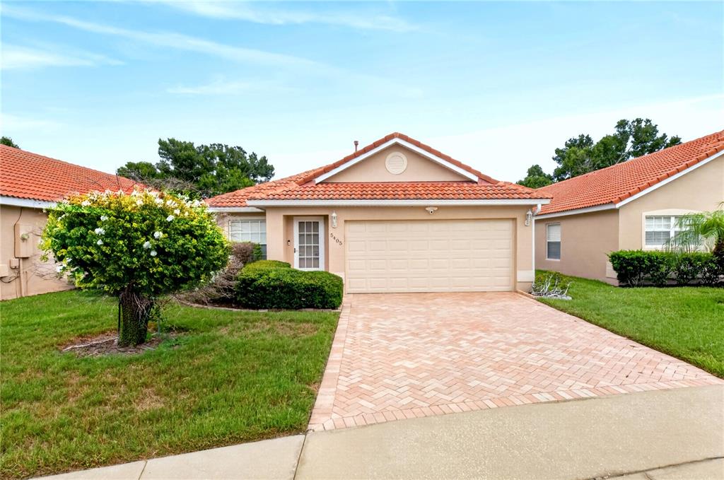 A single-story house with a tan stucco exterior, red tile roof, and a paved driveway — 5405 WATERVISTA DRIVE, ORLANDO, FL