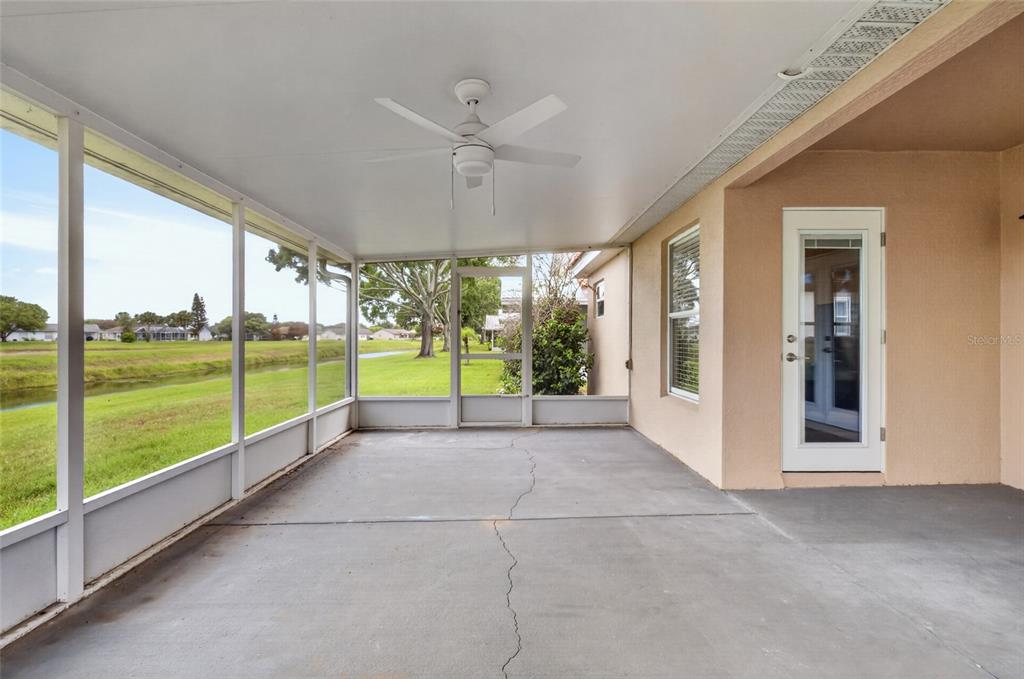 A screened-in patio with a concrete floor, ceiling fan, and a view of a canal — 5405 WATERVISTA DRIVE, ORLANDO, FL