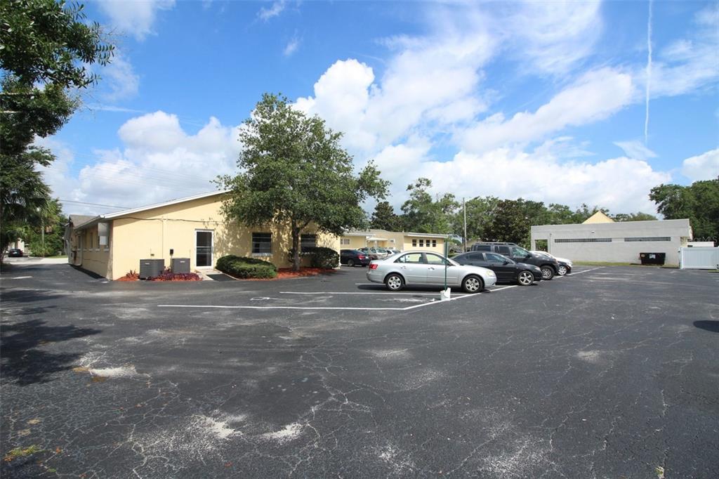 A yellow commercial building with a large asphalt parking lot and several parked cars — 407 LAKE HOWELL ROAD, MAITLAND, FL