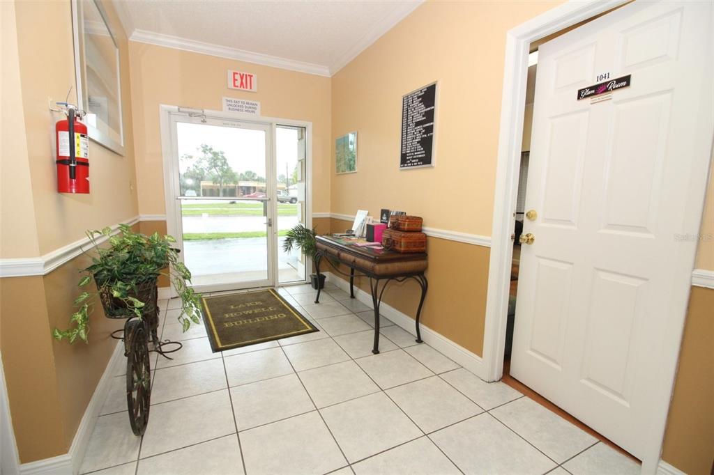 A tiled building entrance features a glass exit door, a console table, and a door labeled Glam Room — 407 LAKE HOWELL ROAD, MAITLAND, FL