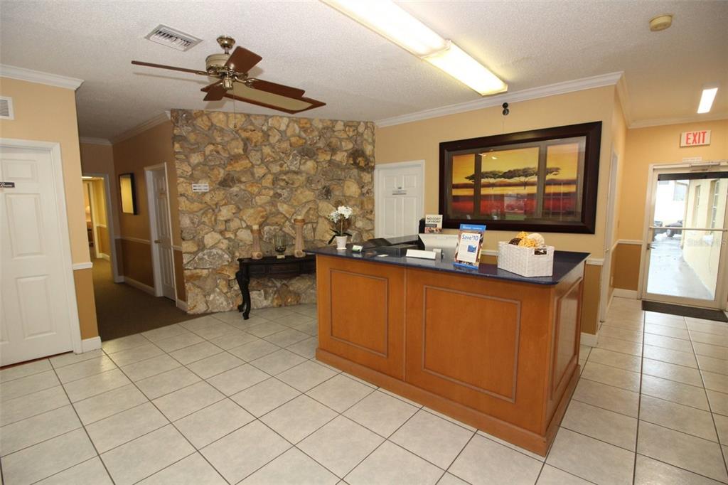 A reception area features a stone accent wall, a wooden desk, and tiled flooring — 407 LAKE HOWELL ROAD, MAITLAND, FL