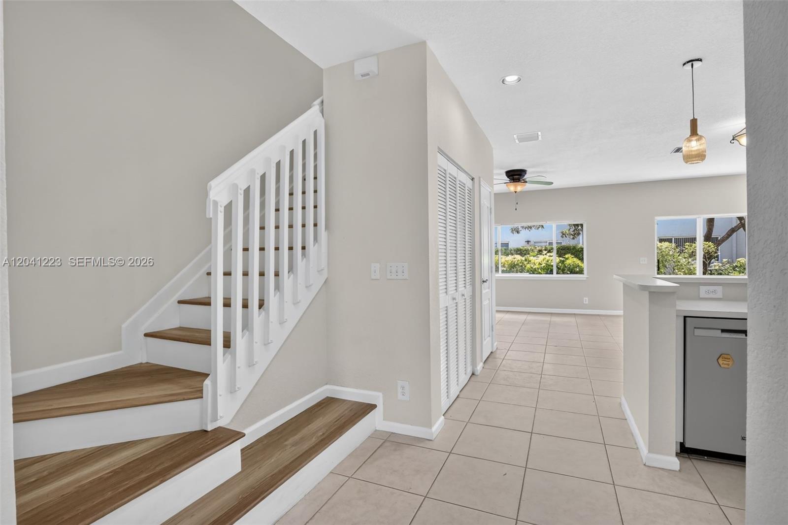 A staircase with wood treads and white railings sits beside a tiled living area — 13212 NW 7th Dr, Plantation FL 33325, PLANTATION, FL