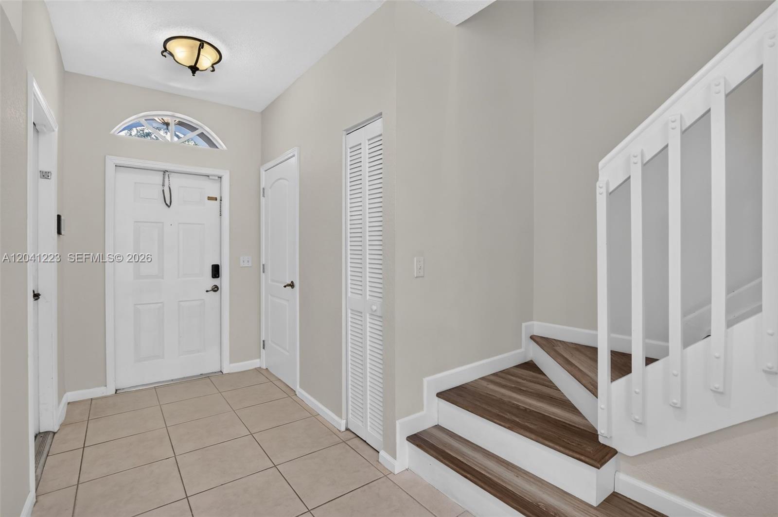 An entryway features tile flooring, a white front door, a closet, and a wooden staircase — 13212 NW 7th Dr, Plantation FL 33325, PLANTATION, FL