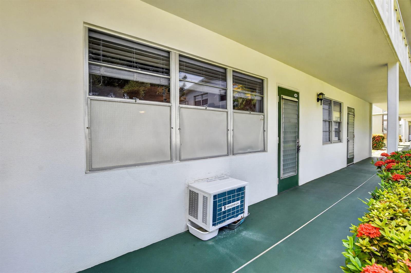 An exterior view of a building with a green walkway, windows, and an air conditioner — 290 OAKRIDGE Q # 290, Deerfield Beach FL 33442, DEERFIELD BEACH, FL