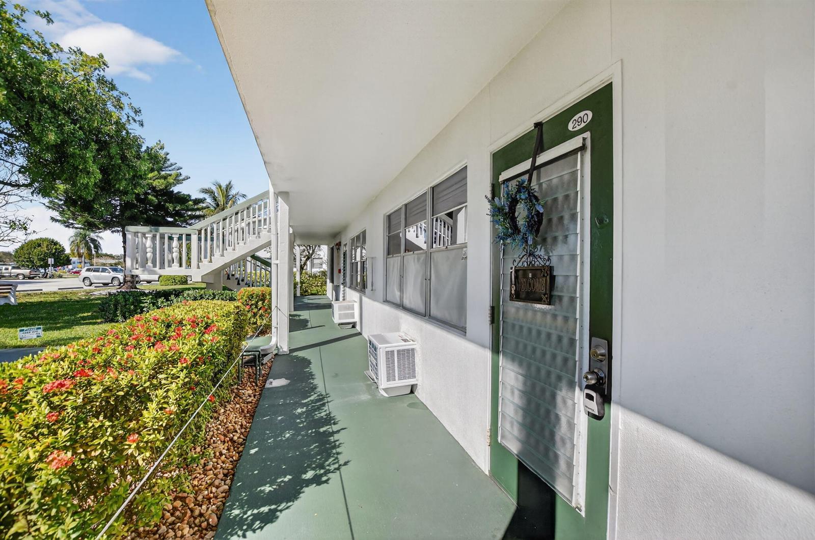 An exterior walkway leads to a green door marked 290 with a small air conditioner — 290 OAKRIDGE Q # 290, Deerfield Beach FL 33442, DEERFIELD BEACH, FL