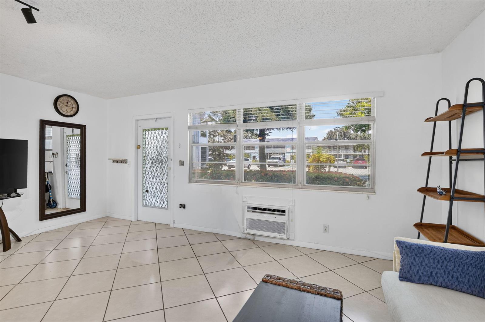 A living room with white walls, tiled floors, a large window, and a wall-mounted air conditioner — 290 OAKRIDGE Q # 290, Deerfield Beach FL 33442, DEERFIELD BEACH, FL