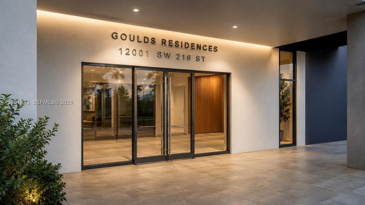 The exterior entrance of a modern building features glass doors and a lit overhang — 0 216 St, Miami FL 33177, MIAMI, FL