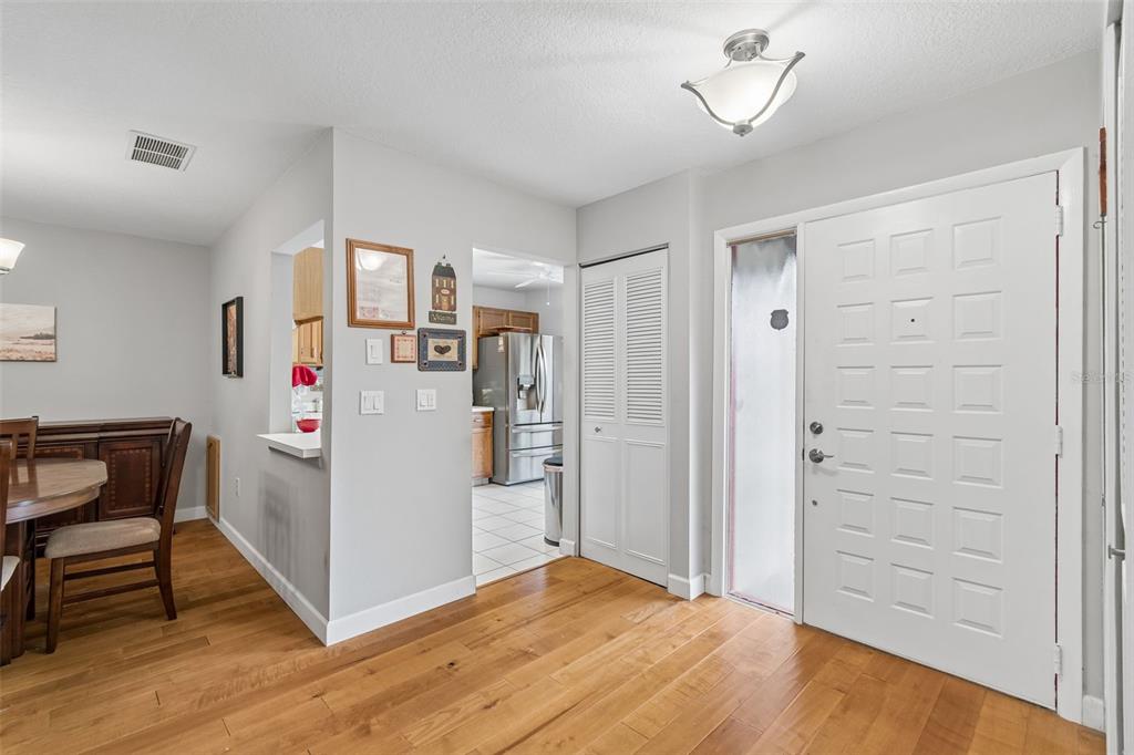 An entryway with hardwood floors, a white front door, and a view into the kitchen — 2903 FIG COURT, PALM HARBOR, FL