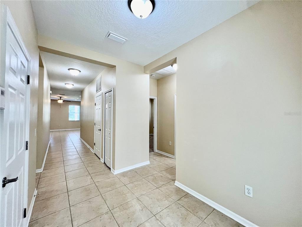 A tiled hallway leads to an open living area with recessed lighting and neutral walls — 9606 OAK GLADE AVENUE, TAMPA, FL