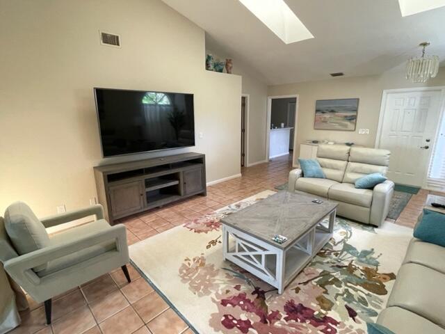 A living room features a television, a media console, a sofa, and an armchair — 1008 Ocean Dunes Circle, Jupiter FL 33477, JUPITER, FL