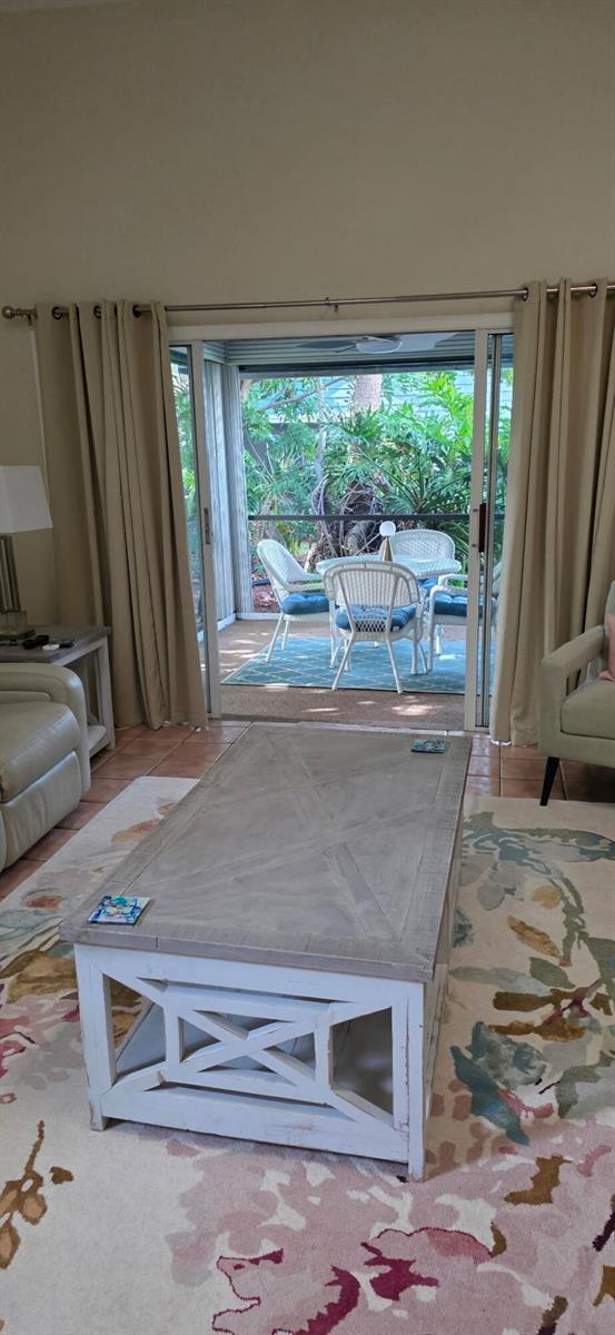 A living room with a coffee table and rug opens to a screened-in patio area — 1008 Ocean Dunes Circle, Jupiter FL 33477, JUPITER, FL