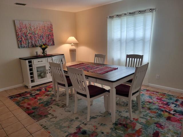 A dining room features a wooden table, white chairs, a matching sideboard, and a colorful rug — 1008 Ocean Dunes Circle, Jupiter FL 33477, JUPITER, FL