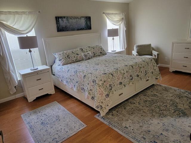 A bedroom features a king bed with floral bedding, two nightstands, and a patterned area rug — 1008 Ocean Dunes Circle, Jupiter FL 33477, JUPITER, FL