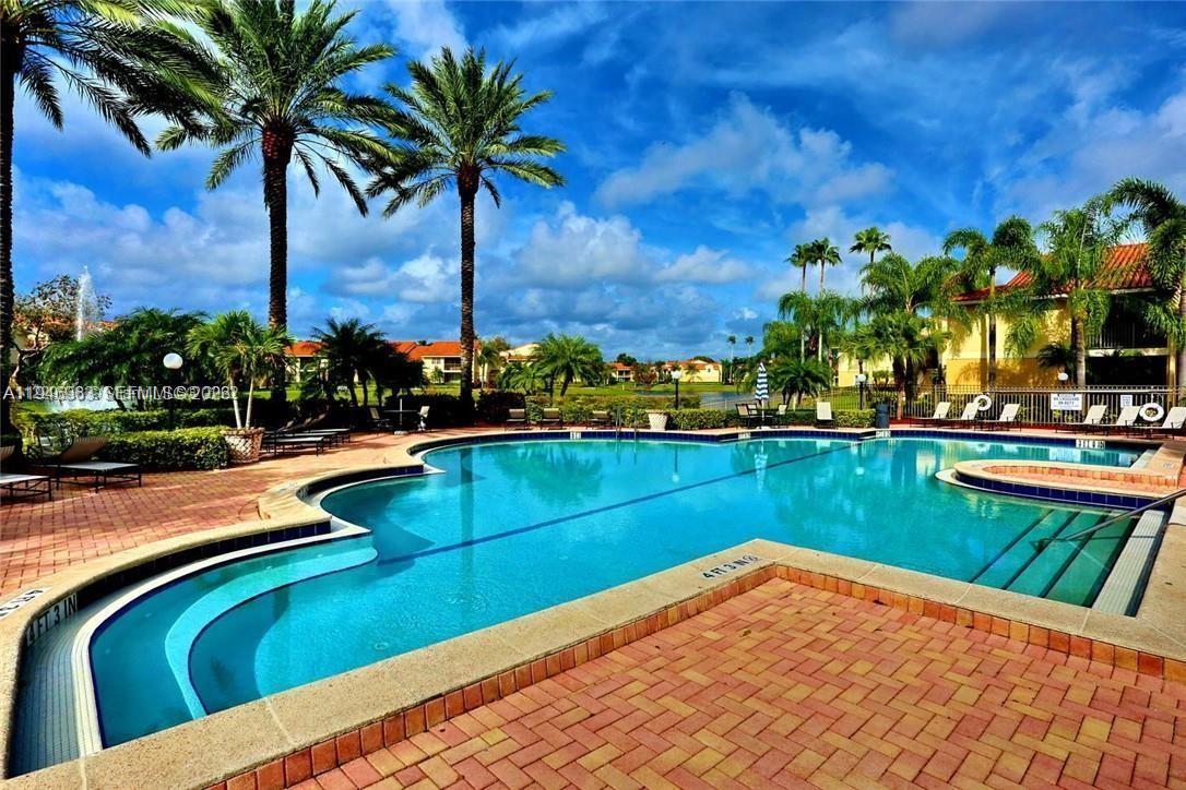 A swimming pool with a brick deck is surrounded by palm trees and apartment buildings — 1239 SW 46th Ave # 903, Pompano Beach FL 33069, POMPANO BEACH, FL
