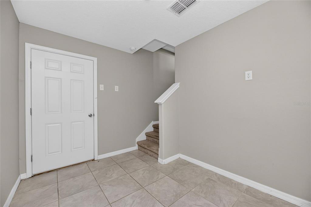 An entryway features a white door, tiled flooring, and a staircase leading to an upper level — 4424 TUSCAN LOON DRIVE, TAMPA, FL