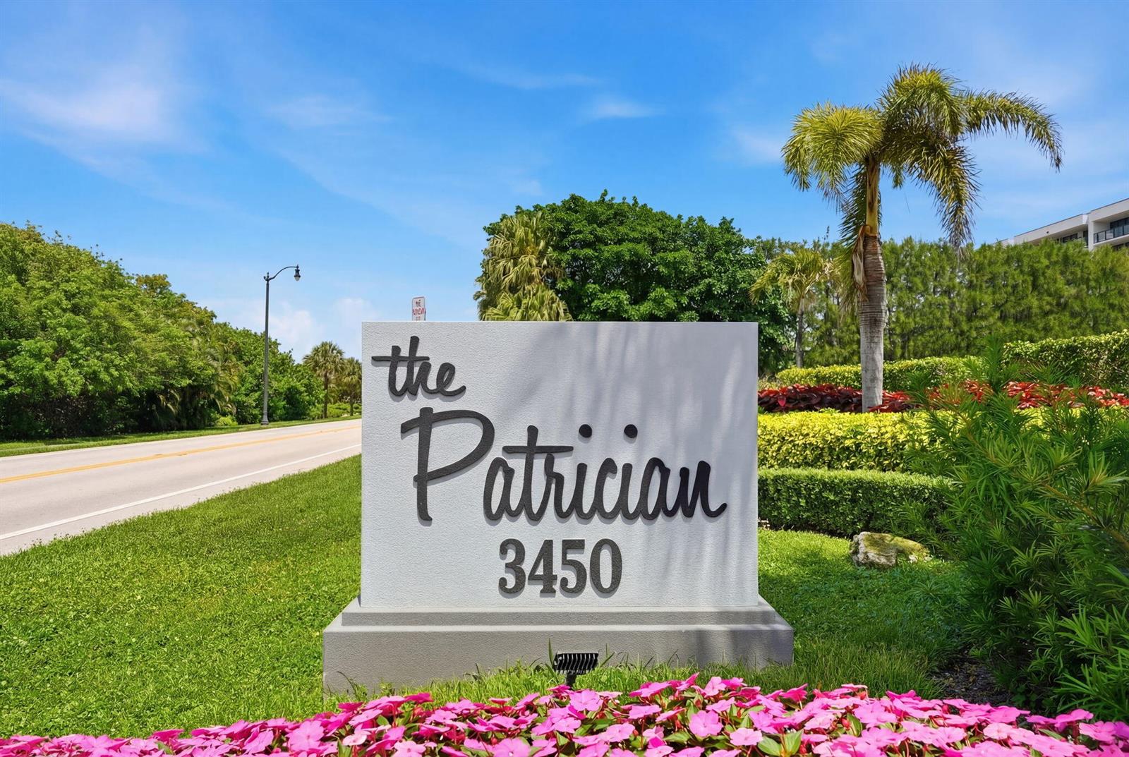 A sign for The Patrician stands in a landscaped garden beside a paved road — 3450 S Ocean Boulevard # 6010, Palm Beach FL 33480, PALM BEACH, FL