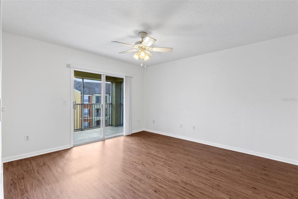 An empty room with wood-look flooring, white walls, a ceiling fan, and a sliding glass door — 12602 CREST SPRINGS LANE UNIT 1331, ORLANDO, FL