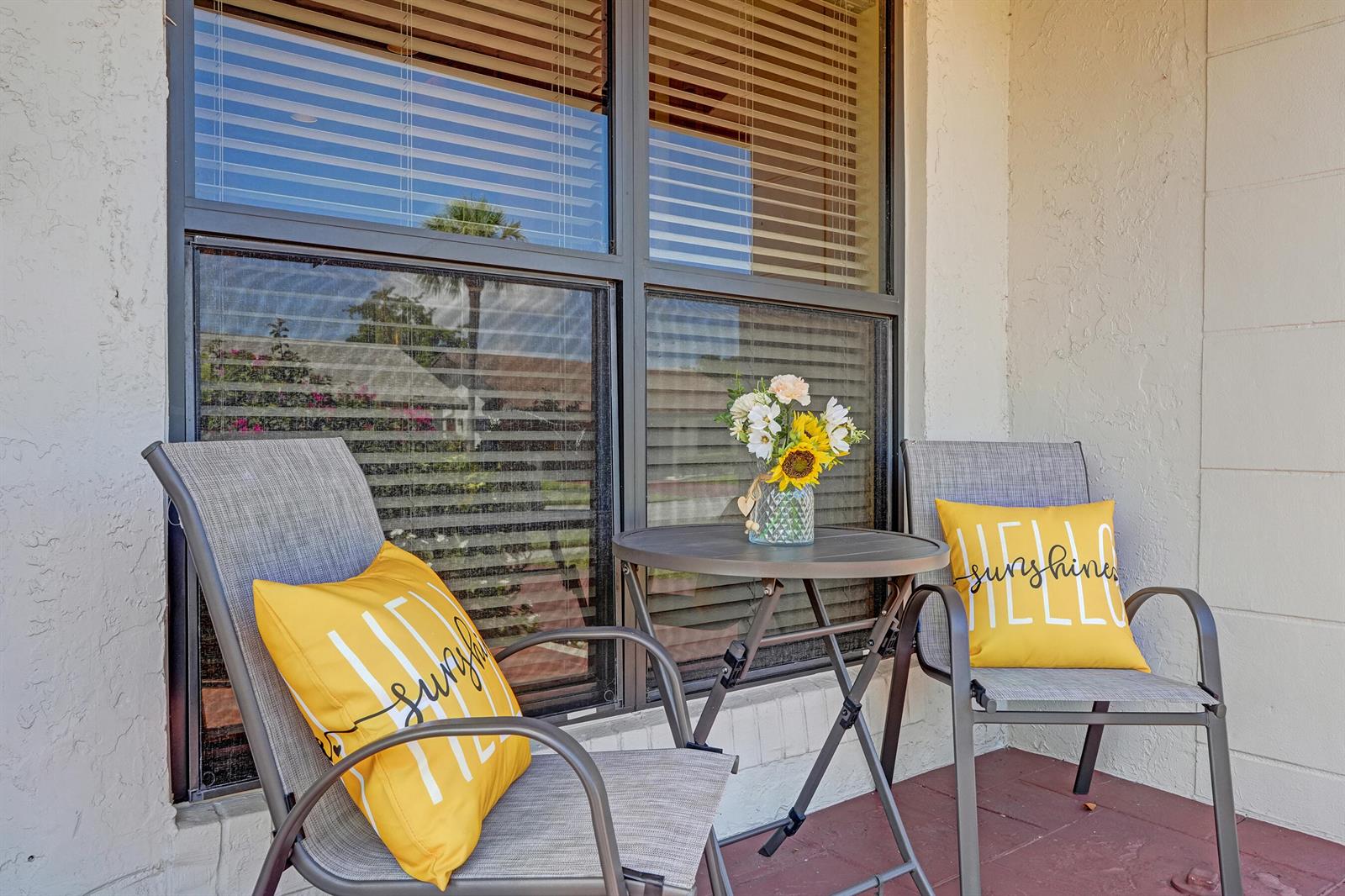 A patio features two gray chairs with yellow pillows and a small table with flowers — 2105 SW 17th Circle, Deerfield Beach FL 33442, DEERFIELD BEACH, FL