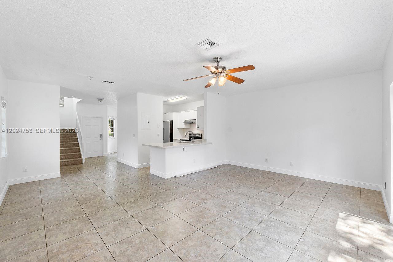 An open-concept living area features tile flooring, a ceiling fan, and a kitchen with white cabinets — 16035 Emerald Cove Rd, Weston FL 33331, WESTON, FL