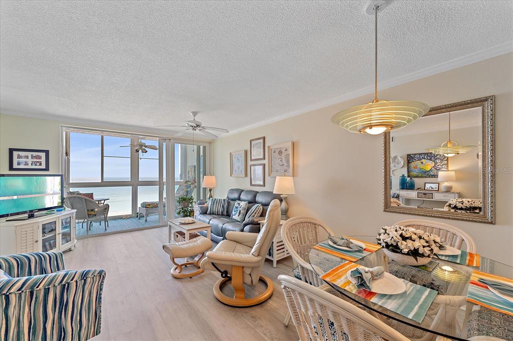 A living and dining area features light wood flooring, a balcony with ocean views, and furniture — 950 TARPON CENTER DRIVE UNIT 504, VENICE, FL