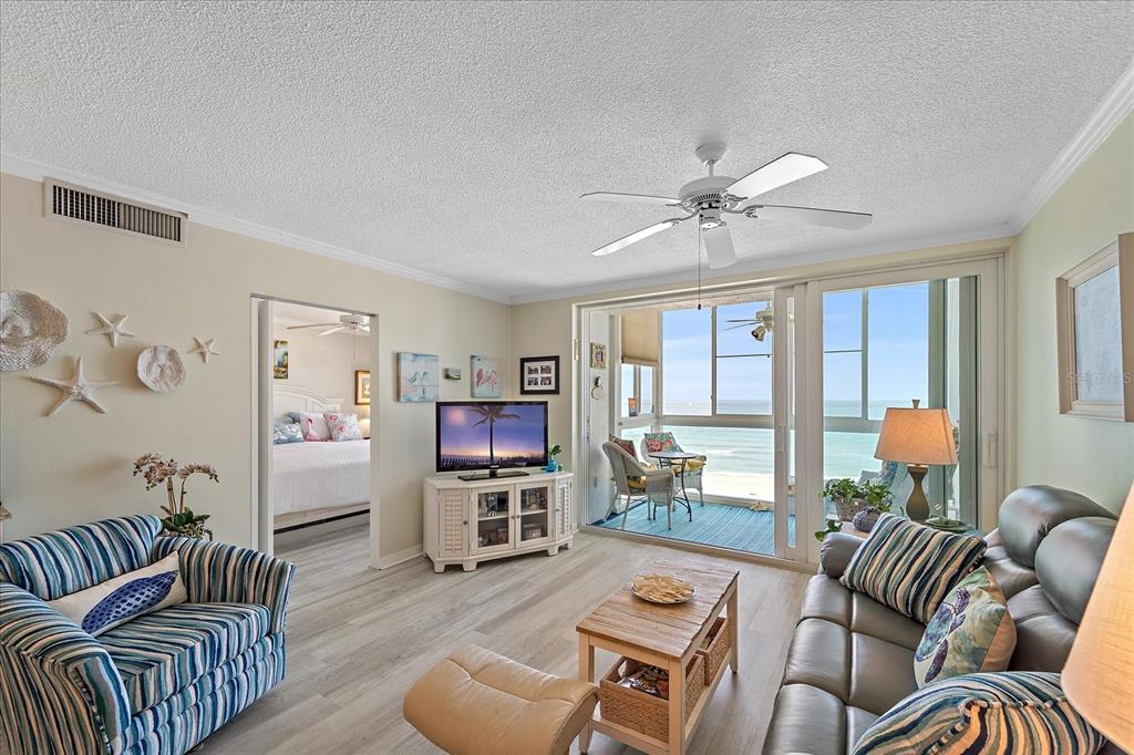 A living room with a striped armchair, leather sofa, television, and sliding doors to a balcony — 950 TARPON CENTER DRIVE UNIT 504, VENICE, FL